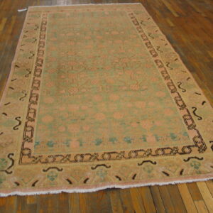 Traditional rug featuring peach and sage green patterns on distressed wooden floorboards.