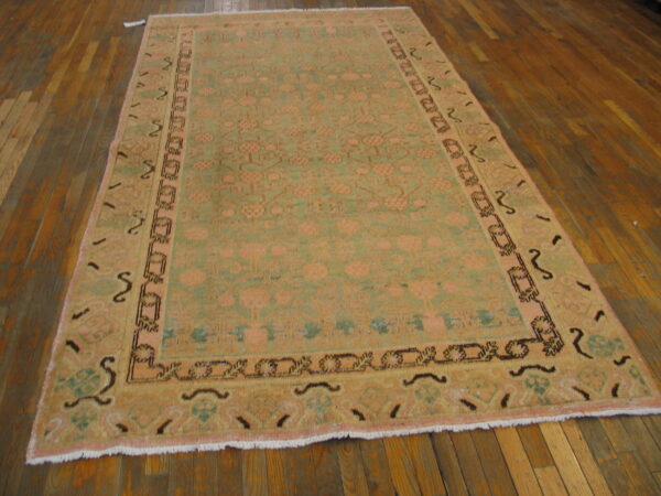 Traditional rug featuring peach and sage green patterns on distressed wooden floorboards.