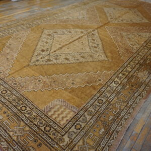Traditional gold and brown rug with complex borders and a large central medallion rests on gray wood flooring.