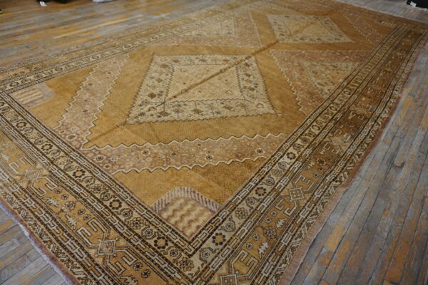 Traditional gold and brown rug with complex borders and a large central medallion rests on gray wood flooring.