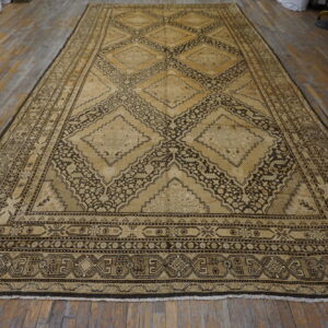 Oversized tan and dark brown rug featuring repeating geometric medallions displayed on plank flooring.
