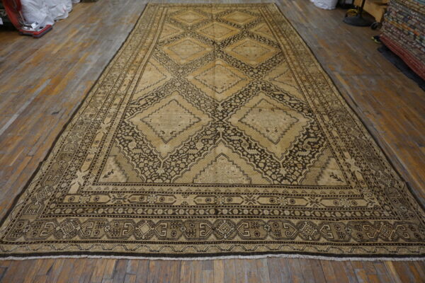 Oversized tan and dark brown rug featuring repeating geometric medallions displayed on plank flooring.