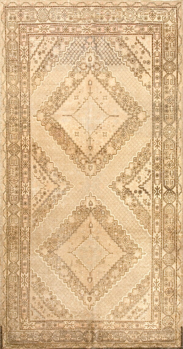 Geometric diamond medallion rug in faded beige and brown tones with extensive patterned borders.