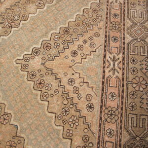 Muted brown and blush rug showing a serrated medallion outline with detailed floral and geometric borders.