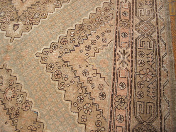 Muted brown and blush rug showing a serrated medallion outline with detailed floral and geometric borders.