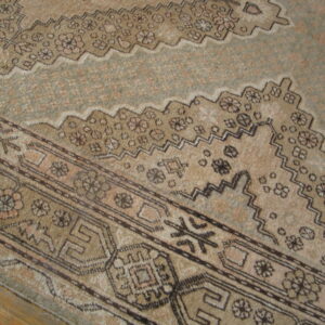 Beige and brown patterned rug detail showing a stepped zigzag border and low pile on wood flooring.