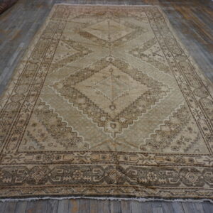 Low-pile beige and brown geometric rug with large central diamonds on a rustic wood floor.