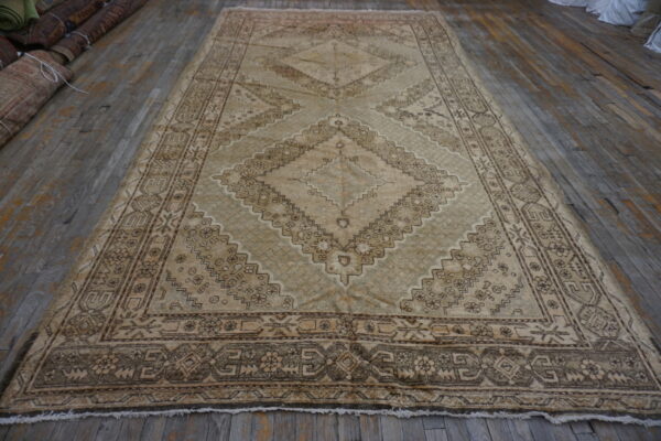 Low-pile beige and brown geometric rug with large central diamonds on a rustic wood floor.