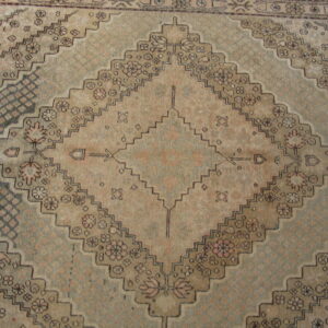 Geometric diamond pattern rug in faded taupe, pale green, and dark brown with small floral motifs.