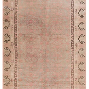 Faded sage rug with dusty pink floral motifs and multi-striped borders featuring dark swirling designs.