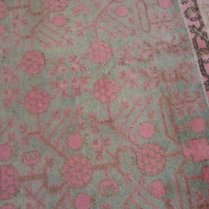 Muted gray-green rug with high pile featuring a traditional pink and brown floral design.