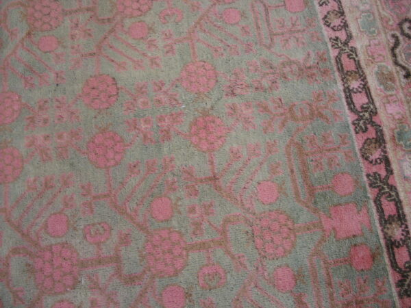 Muted gray-green rug with high pile featuring a traditional pink and brown floral design.