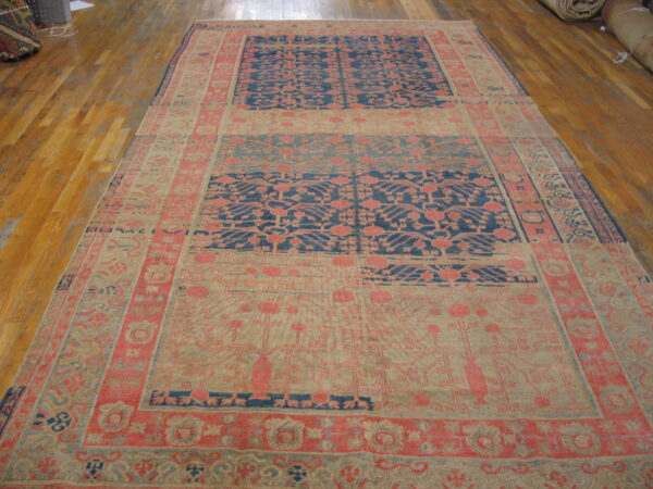Large rug with complex coral and blue paneled patterns rests on glossy wood flooring.