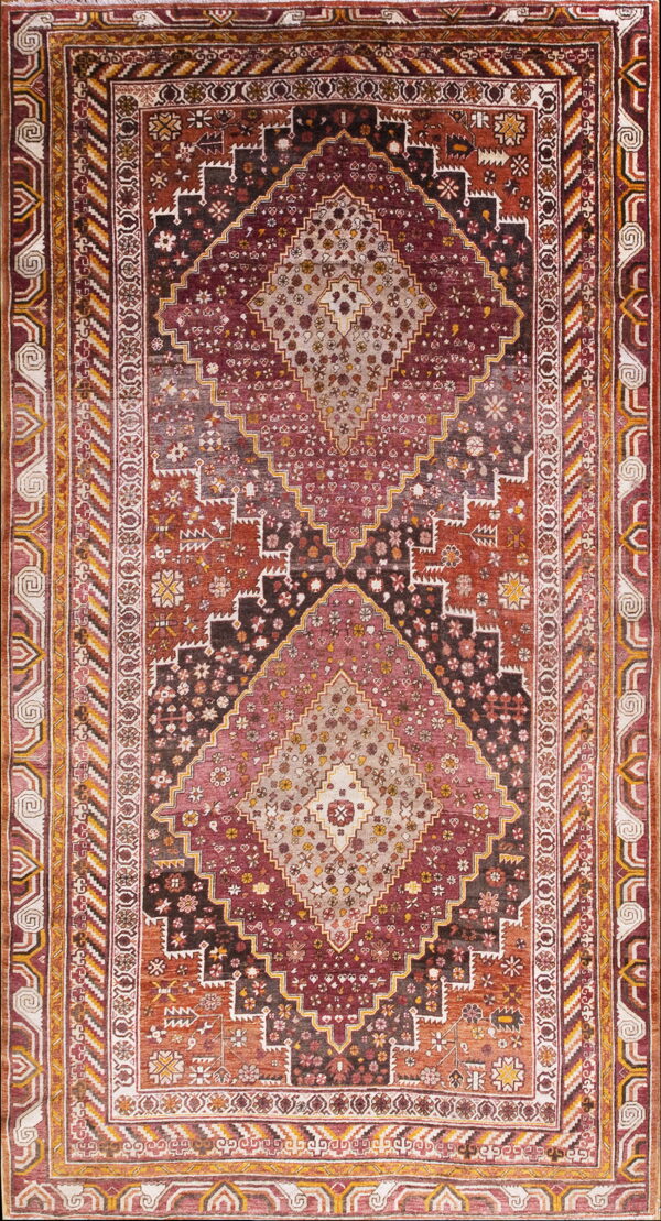 Traditional rug with a large stepped diamond pattern in deep red, rust, and beige tones.