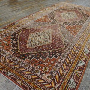 Distressed rug with intricate red, orange, and gold geometric patterns centered on wide gray hardwood planks.