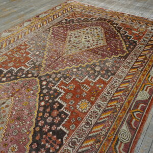 Geometric central medallion rug in earth tones, burgundy, and gold accents rests on weathered wood planks.