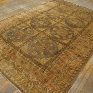 Brown and gold rug with a large geometric medallion pattern rests on distressed wood flooring.