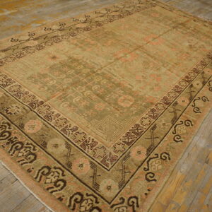 Low-pile traditional rug in muted olive, tan, and pink geometric patterns on distressed wood planks.