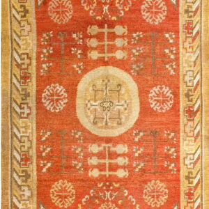 Reddish-orange low-pile rug featuring a central medallion and complex gold and brown geometric borders.