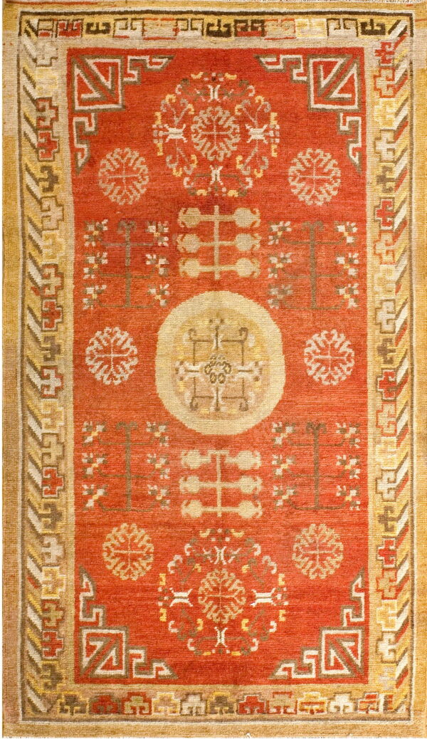 Reddish-orange low-pile rug featuring a central medallion and complex gold and brown geometric borders.