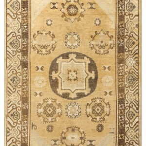 Tan rug with a dark brown central medallion and bold multi-layered geometric borders.