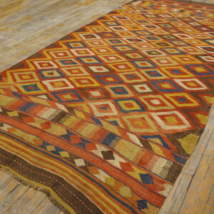 Flatweave rug with a central diamond pattern and striped borders in vibrant orange, yellow, and blue.