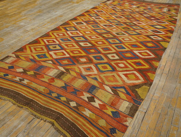 Flatweave rug with a central diamond pattern and striped borders in vibrant orange, yellow, and blue.