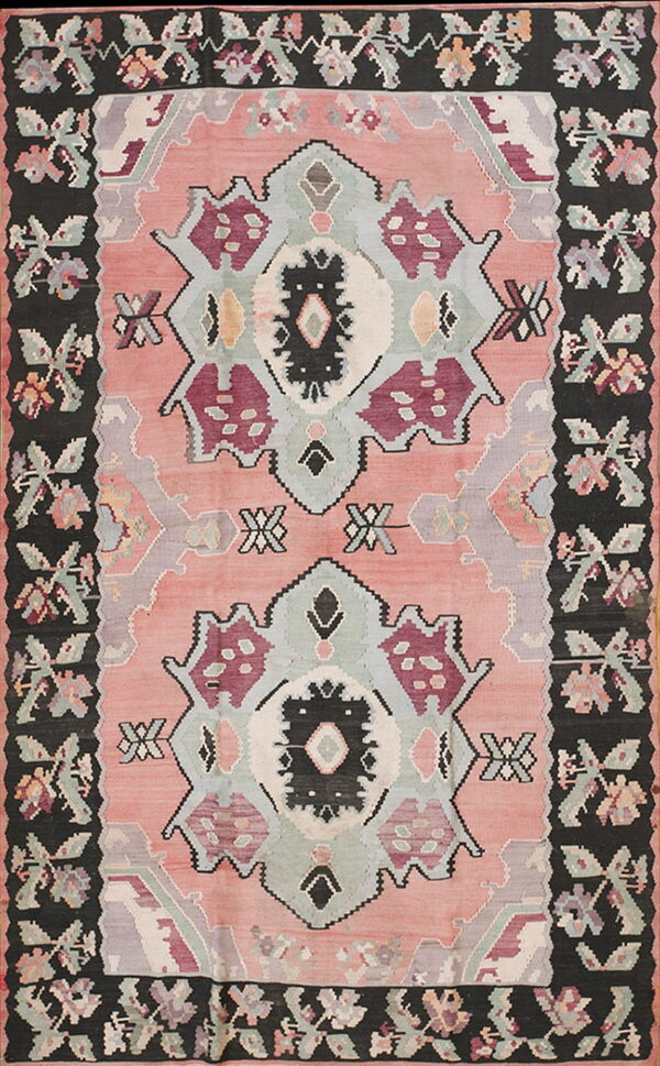 Pink flatweave rug with stacked geometric medallions and a wide black border of stylized floral designs.