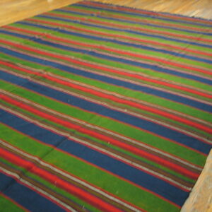 Green, blue, and red striped flatweave rug displayed on light natural wood plank flooring.