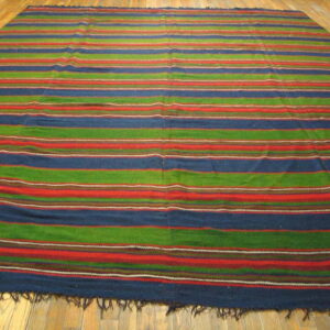 A low-pile rug with blue, green, and red horizontal stripes covers light wood plank flooring.
