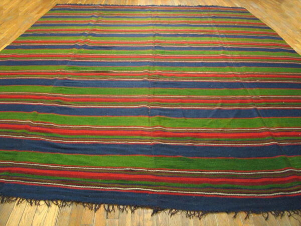 A low-pile rug with blue, green, and red horizontal stripes covers light wood plank flooring.