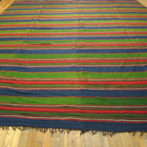 Large striped rug featuring blue, green, and red horizontal bands on a light wooden plank floor.