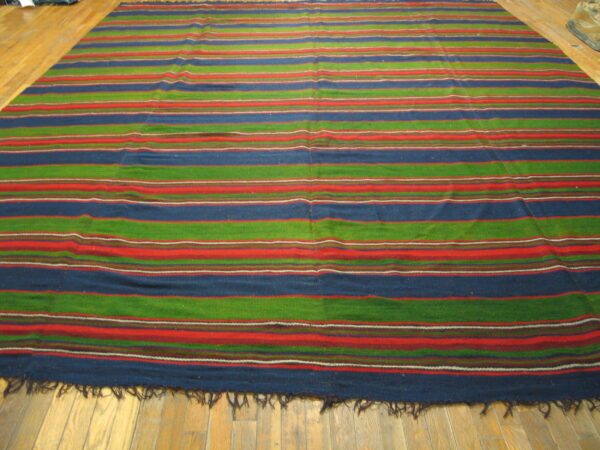Large striped rug featuring blue, green, and red horizontal bands on a light wooden plank floor.