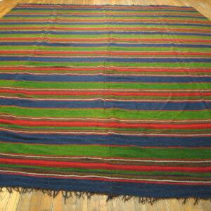 A low-pile rug featuring wide horizontal stripes in blue, green, and red rests on a wood plank floor.