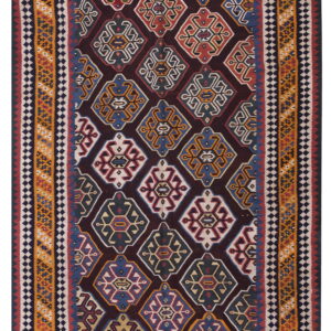 Low-pile rug with a dark field, repeating multicolored geometric diamond medallions, and striped borders.