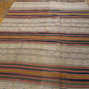 Low-pile rug with horizontal stripes in navy, rust, mustard, and green, resting on honey wood floors.