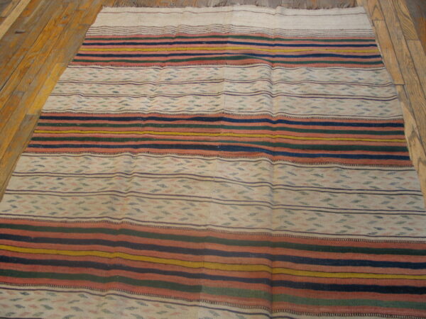Low-pile rug with horizontal stripes in navy, rust, mustard, and green, resting on honey wood floors.