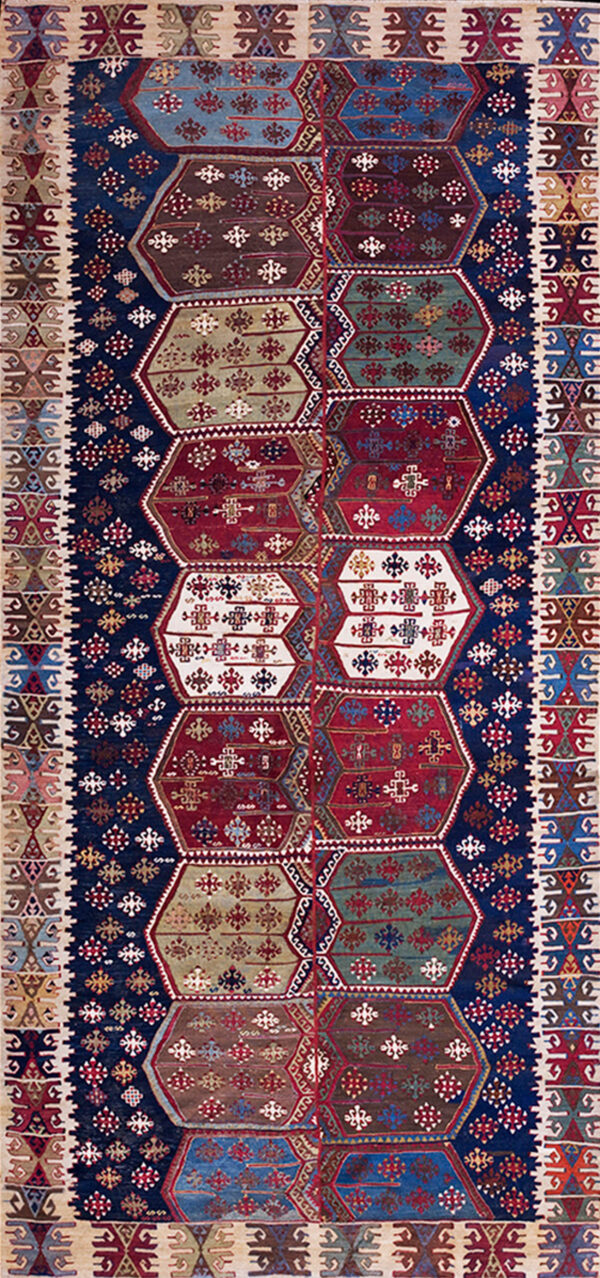 Detailed geometric rug with a navy background and alternating red, green, blue, and white polygonal medallions.