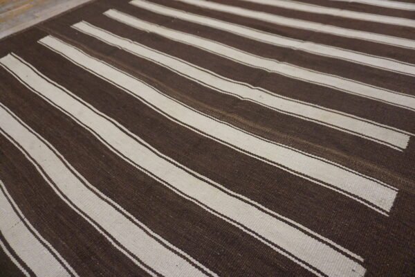 Flatweave rug with broad horizontal stripes in dark brown and contrasting off-white colors.