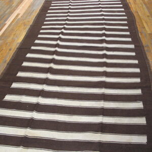 Dark brown and cream striped runner rug displaying a flatweave texture on wood flooring.