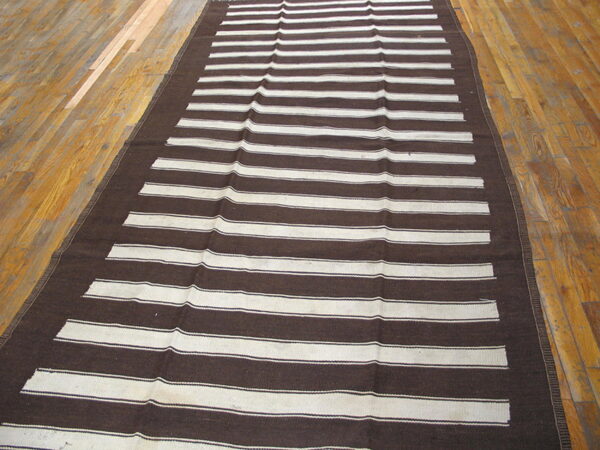 Dark brown and cream striped runner rug displaying a flatweave texture on wood flooring.