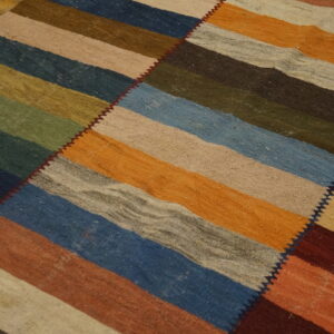 Flat woven rug with wide multi-colored horizontal stripes sewn diagonally, lying on a wood floor.