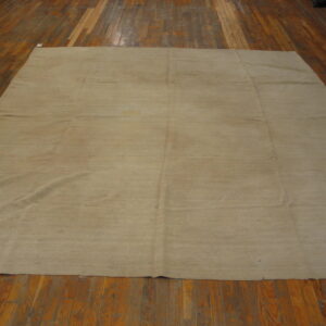 Solid light khaki rug with horizontal banding displayed across reddish-brown wood plank flooring.