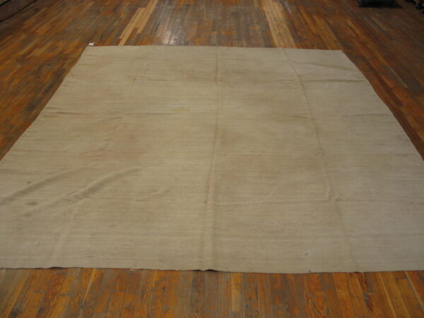 Solid light khaki rug with horizontal banding displayed across reddish-brown wood plank flooring.