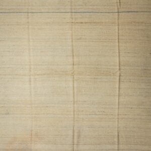 Solid cream flatweave rug with short fringes lies on worn natural hardwood flooring.