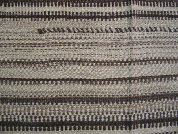 Textured flatweave rug in natural beige and dark brown, featuring alternating horizontal striped and dotted patterns.