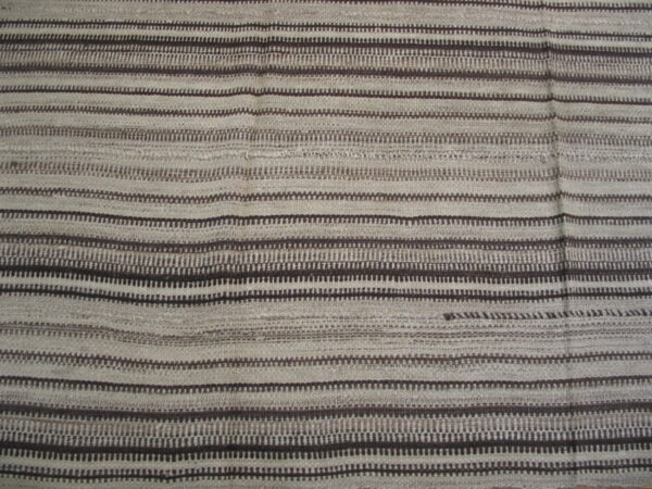 Textured rug featuring wide pale gray bands alternating with narrow dark brown geometric striped patterns.