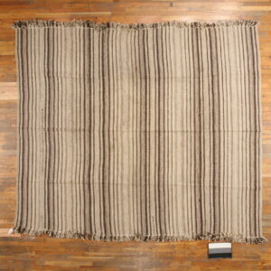 Flatwoven rug featuring light tan and dark brown vertical stripes resting on a wood floor.
