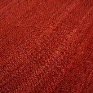 The vibrant red, textured rug features visible patchwork seams resting on light wood flooring.