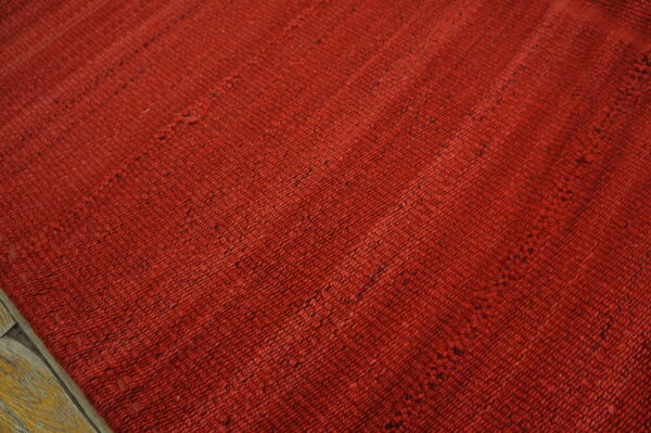 The vibrant red, textured rug features visible patchwork seams resting on light wood flooring.
